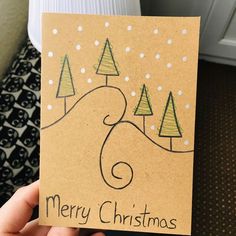 someone holding up a christmas card with trees on it