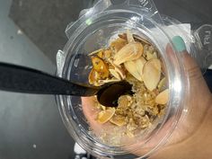 a person holding a plastic container filled with oatmeal and granola toppings