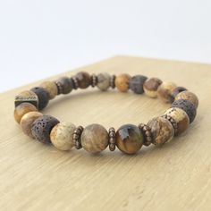 Picture jasper and Tiger's Eye complete this nurturing, grounding and earthy bracelet, bringing confidence and relief from stress. Picture jasper is a harmonizing stone with a strong connection to the earth. It is said to promote feelings of responsibility towards the planet, encouraging a need to care for and protect it. Picture Jasper- Nurturing, Protective, Brings Comfort, Alleviates Fear Tiger's Eye- Will Power, Confidence, Releases Anxiety Lava - Balance, Grounding, Strength, Balance Stone Aromatherapy Crafts, Male Inspiration, Men Stone Bracelet, Man Jewelry, Will Power, Brown Gemstone, Beads Bracelet Design, Diy Recycle, Braided Leather Bracelet