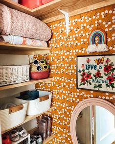 a bathroom with yellow wallpaper and white baskets on the shelves next to a mirror