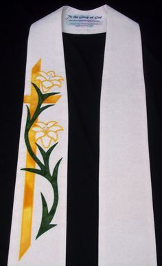 a white scarf with yellow and green flowers painted on the front, along with a black background