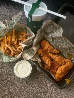 chicken and french fries are sitting on the floor next to a drink