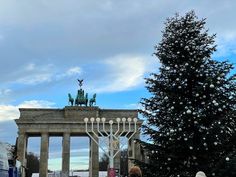 a large christmas tree in front of a building with a lit menorah on it