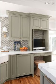 a kitchen with gray cabinets and white counter tops, wood flooring and a large tv mounted on the wall