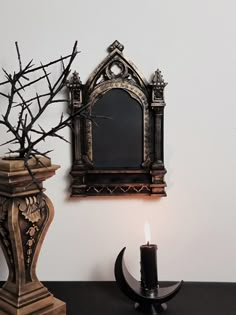 a candle is sitting next to a mirror on the wall and a vase with branches in it