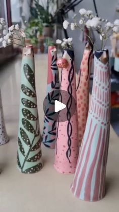 four vases with flowers in them sitting on a table next to a planter