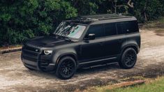 the black suv is parked in front of some trees