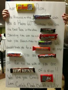 a person holding up a sign with candy bars on it and writing in the middle