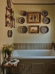 a bath tub sitting next to a wall filled with pictures and plates on it's side