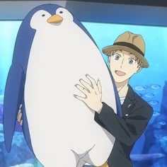 a man holding a penguin in front of an aquarium