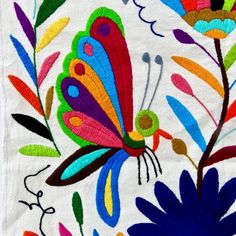 an embroidered butterfly on white fabric with colorful flowers