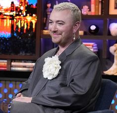 a man sitting in a chair with a flower on his lap and smiling at the camera