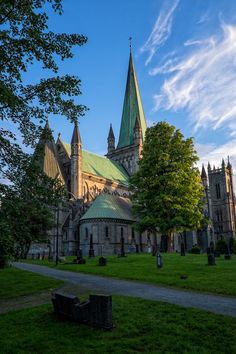 an old church with green roof and steeples on it's sides, surrounded by trees