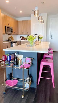 a kitchen island with pink stools next to it