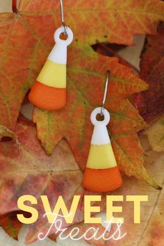 two orange and white candy cornucons are hanging from earwires with the words sweet treats written on them