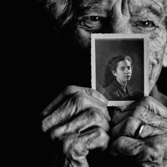 an old woman holding up a small photo