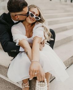 a man and woman are sitting on the steps together, one is holding her arm around the other's shoulder