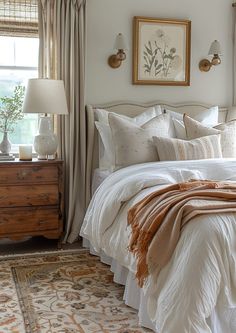 a bed with white linens and pillows in a bedroom next to a painting on the wall