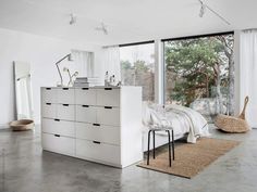 a bedroom with white furniture and large windows