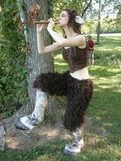 a woman dressed in costume standing next to a tree