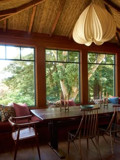 a dining room table and chairs in front of large windows with wooden beams on the ceiling