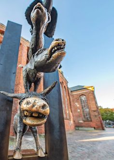 a statue of a dog and a cat on top of each other in front of a building