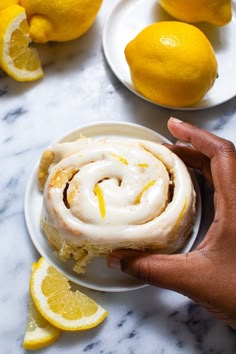 a person holding a piece of food on top of a plate next to lemons