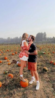 a man and woman kissing in a pumpkin patch