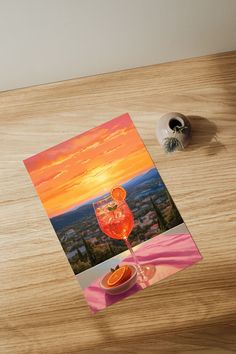 an orange slice and wine glass on a wooden table with a view of the city