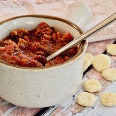 a white bowl filled with chili and crackers