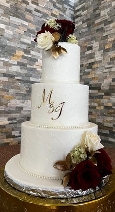 a three tiered white wedding cake with red and white flowers