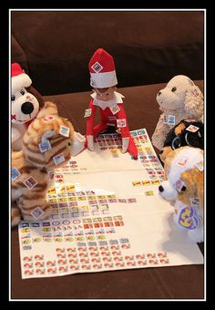 four stuffed animals are sitting at a table with stickers on it and one has a santa hat