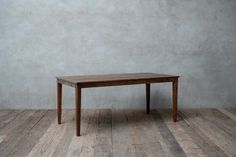 a wooden table sitting on top of a hard wood floor next to a white wall