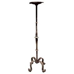 a metal pole with three candles on it and an iron stand in the shape of a flower