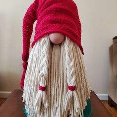 a doll is wearing a red and white knitted hat with long, braided hair