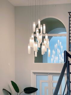 a modern chandelier hanging from the ceiling in a foyer with stairs leading up to it