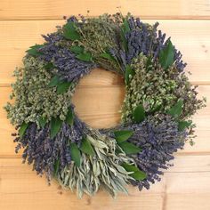 a wreath made out of lavenders and leaves on a wooden table with wood planks