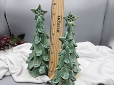 two ceramic christmas trees sitting next to a ruler