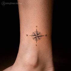 a small compass tattoo on the side of a woman's foot, which is black and white