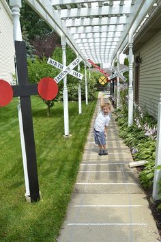 a little boy that is standing in the grass with a cross and street signs on it