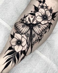 a black and white butterfly with flowers on it's leg, done by person