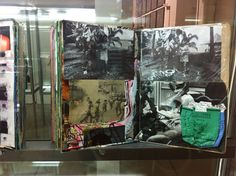 an open book on display in a glass case with pictures and other items around it