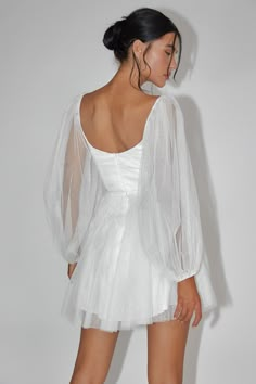 a woman wearing a white dress with sheer sleeves