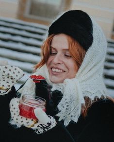 a woman holding a jar of jam in her hand and smiling at the camera while wearing mittens