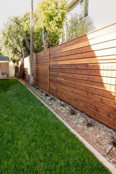 a fenced back yard with grass and trees in the background that reads, a fenced