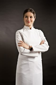 a woman wearing a white chef's coat posing for the camera with her arms crossed