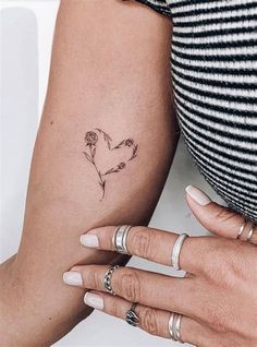 two hands holding each other with tattoos on their arms and one has a flower in the shape of a heart