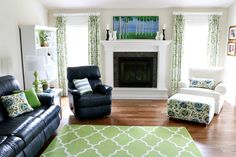 a living room filled with black leather furniture and green pillows on top of a rug