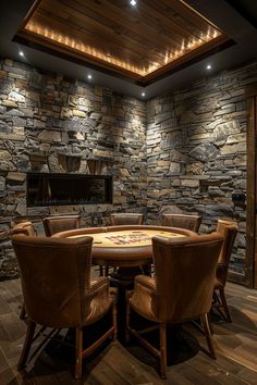 a dining room with stone walls and wooden chairs around a round table that is surrounded by brown leather chairs