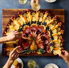 people are making a turkey shaped platter out of fruits and cheeses on a table